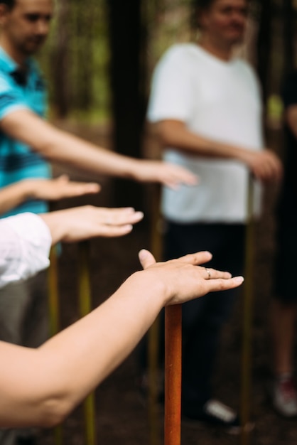 Vertical photo of people standing in a circle and holding a stick team building exercise high