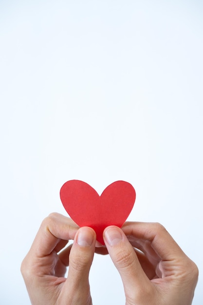 Vertical photo of two hands holding a heart on white background with copy space