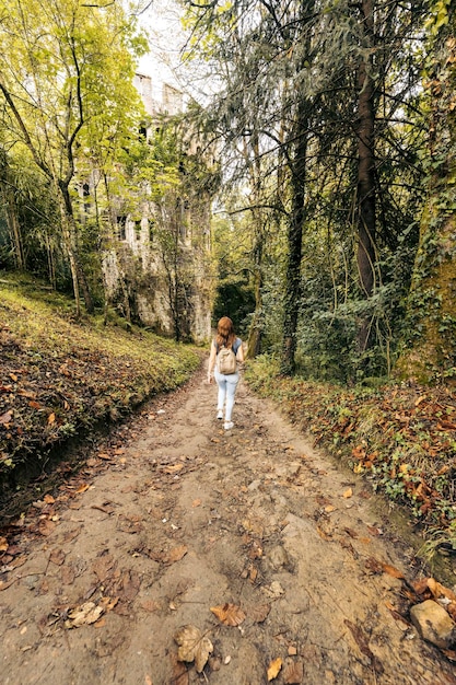 Vertical photo of a woman walking along a path surrounded by trees