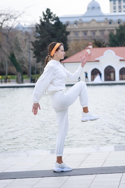 Vertical photo of young athlete raised her leg and doing her exercise High quality photo