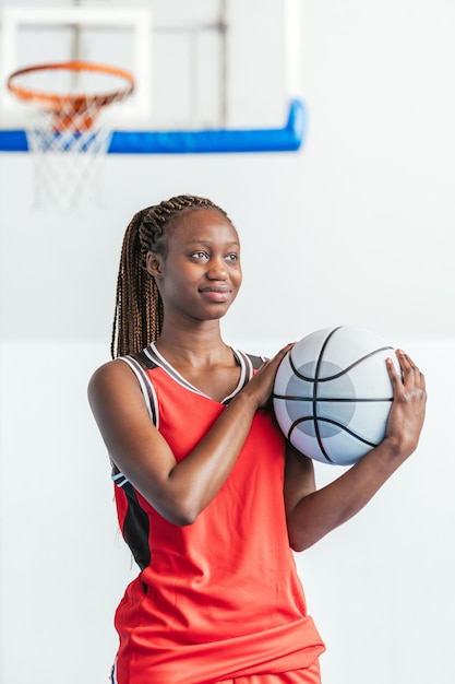 Vertical photo young female basketball player in red uniform holding ball Sport concept