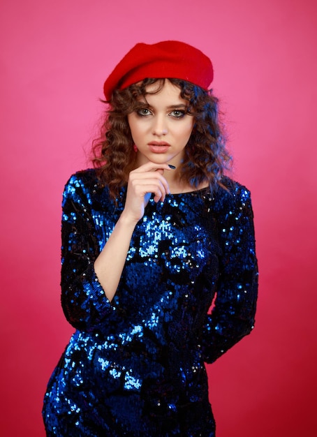 Vertical photo of young lady stand on pink background and put her finger to her chin High quality photo