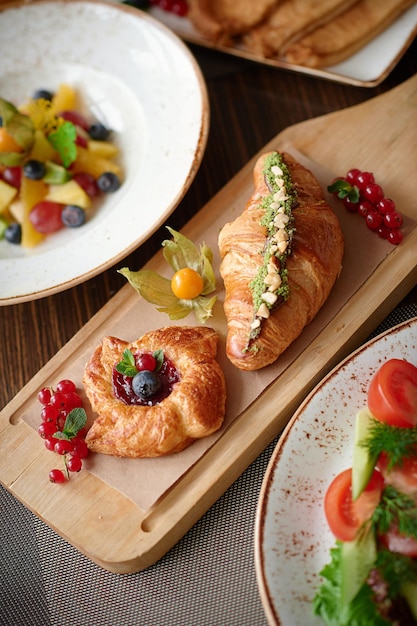 Vertical photography with bakery and fruit salad on the wooden boarddecorated with physalis