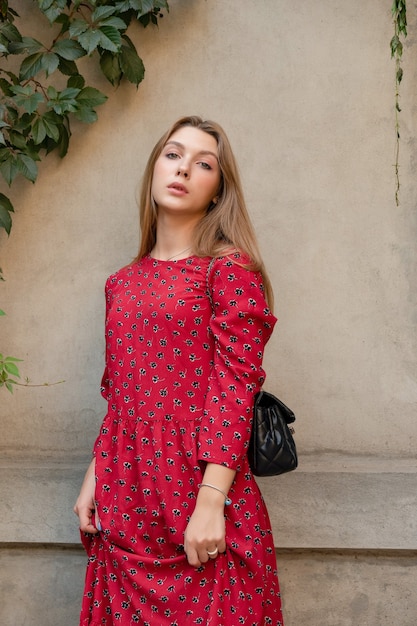 Vertical Portrait of a beautiful blonde girl with longhair in a dress standing on a beige background