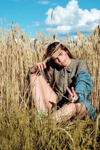 Vertical portrait of beautiful young woman in the field. girl in ears of wheat on hot summer field outdoors, fashion and model teenager.