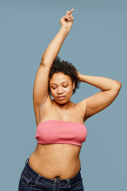 Vertical portrait of carefree black woman posing against pastel blue background