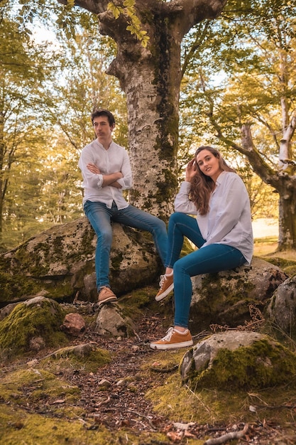 Vertical portrait of a casual couple in denim clothes sitting on a forest