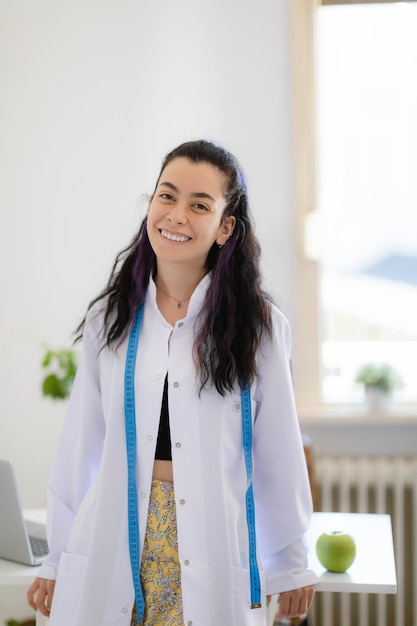 Vertical portrait of dietitian nutrtionist doctor wearing lab coat looking to camera and smiling