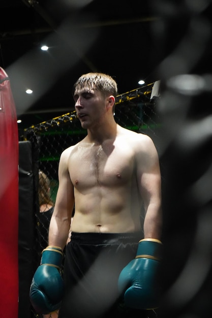 Vertical portrait of a male boxer wearing gloves during training at striking gym