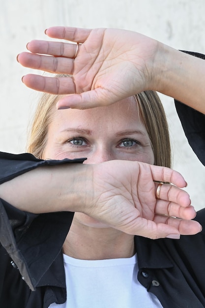 Vertical portrait of young blonde woman with hands covering face and only show visible look of her beauty eyes