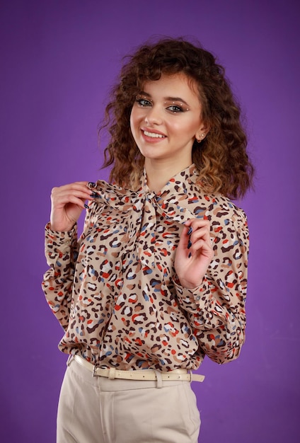 A vertical portrait of a young curlyhaired girl smiling and put her hands to her chest High quality photo