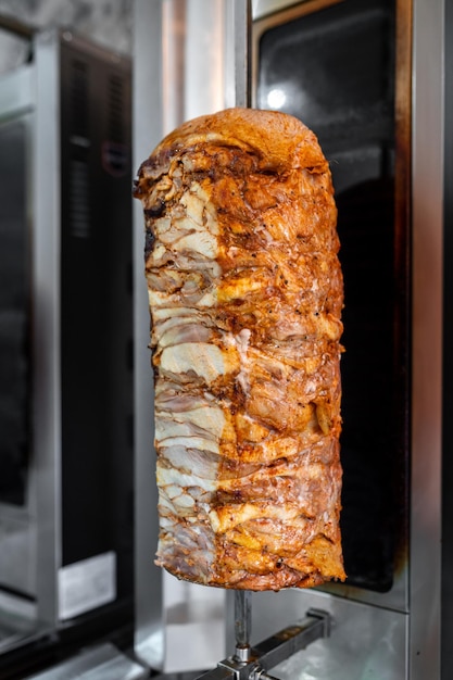 Vertical rotisserie marinated chicken meat for Doner Kebab Turkish street food