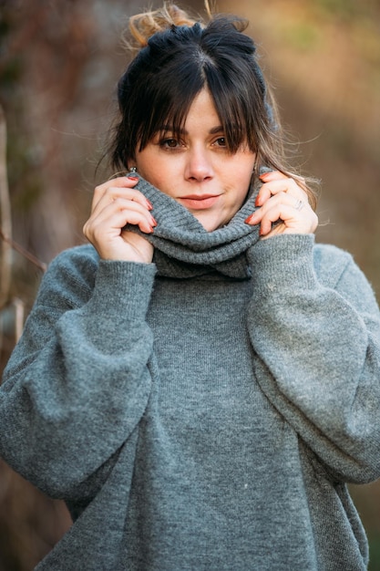 Vertical selective focus shot of a young lady wearing a gray turtleneck sweater