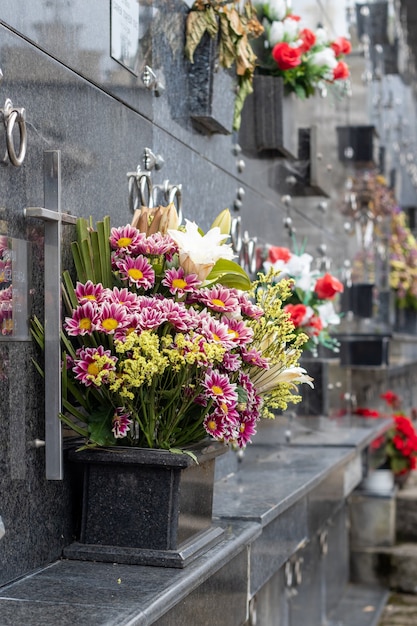 Vertical shallow focus shot of bouquets below dark marble tombstones at the cemetery