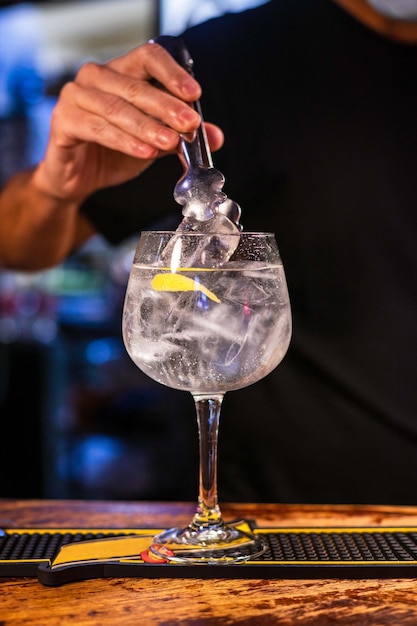 Vertical shot of a barman preparing gin tonic