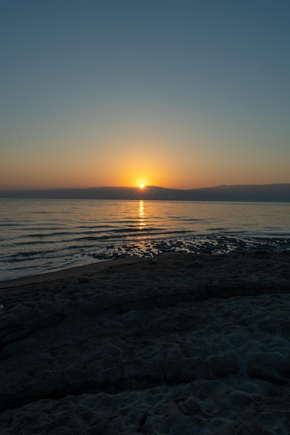 Vertical shot of a beach surrounded by the sea during the sunrise in the morning