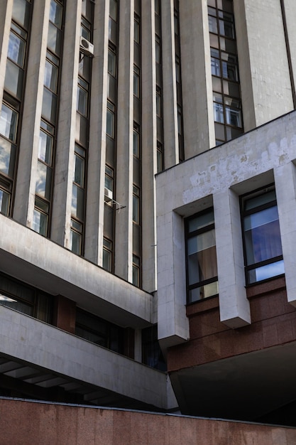 Vertical shot of a building with a white facade and reflection of the sky in the windows