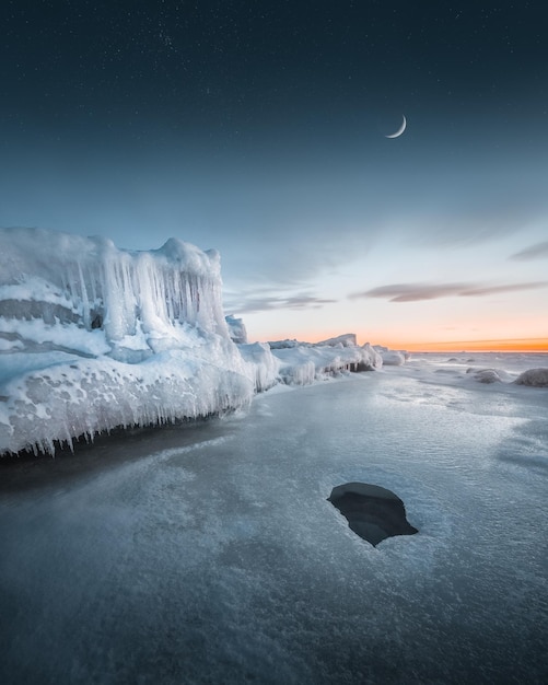 Vertical shot of a cold icy arctic area with frozen water and glaciers at sunset