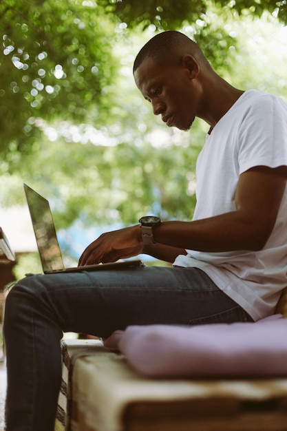 Vertical shot of concentrated modern multiracial man work on laptop typing International student elearning education