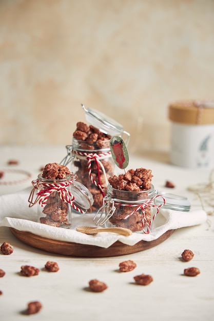 Vertical shot of delicious Christmas roasted almonds in a jar on a wooden plate