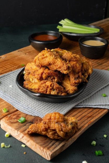 Vertical shot of delicious crispy fried chicken ketchup gravy and celery sticks on a wooden table