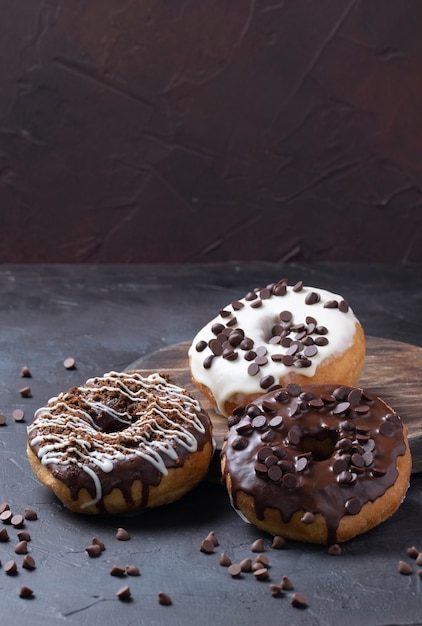 Vertical shot of glazed donuts topped with chocolate chips on a rustic surface