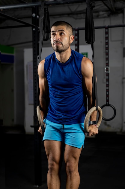 Vertical shot of a gymnast doing ring dips in the haros of a gym