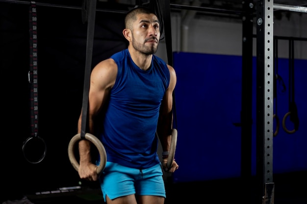 Vertical shot of a gymnast doing ring dips in the haros of a gym