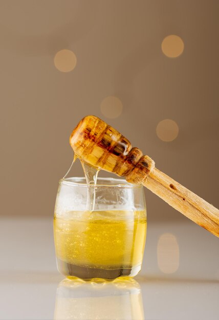 Vertical shot of honey dipping in a transparent glass from a dipper