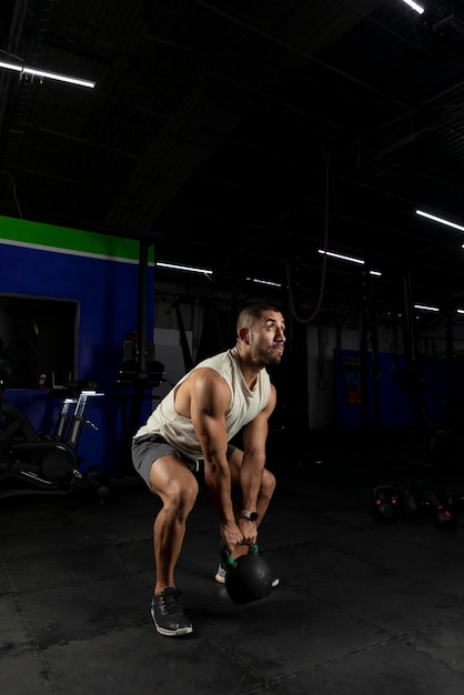 Vertical shot of a Latino man exercising in a gym using a kettlebell