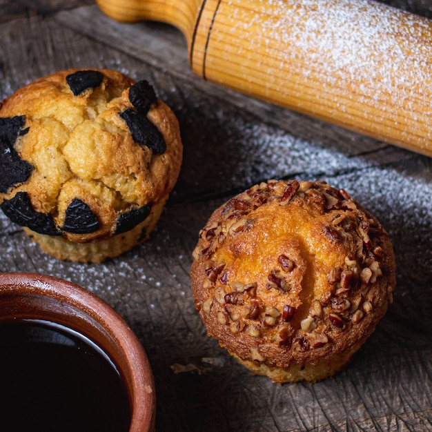 Vertical shot of a muffin with almonds a rolling pin a muffin with cookies and a bowl of syrup