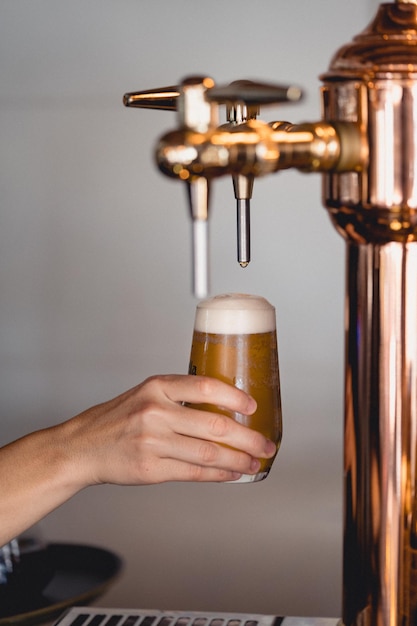 Vertical shot of a person filling the glass with beer