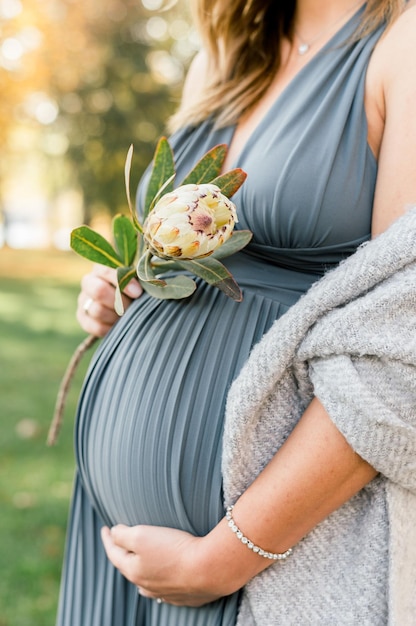 Vertical shot of a pregnant woman holding a flower in Germany