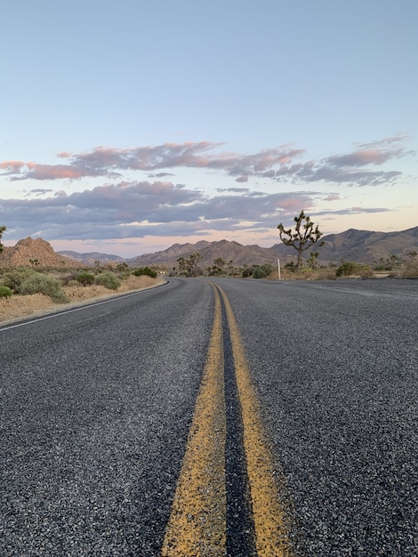 Vertical shot of a road through hills and mountains during sunset