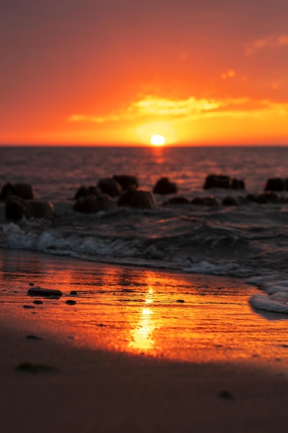 Vertical shot of rocks on the beach on a bright sunset sky background