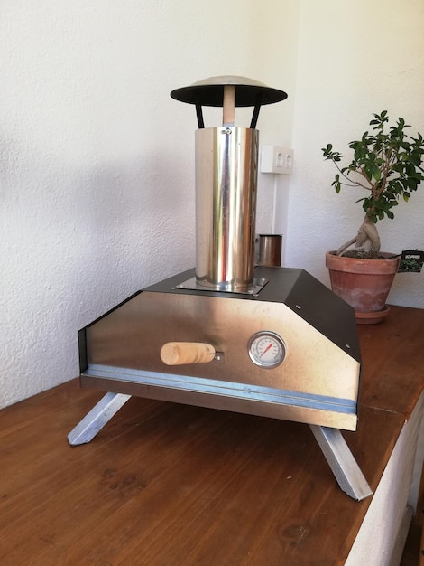 Vertical shot of a silver pizza oven on a wooden table in the kitchen