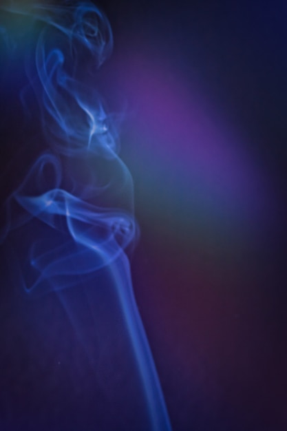 A vertical shot of smoke in colorfull backlight with a blue note