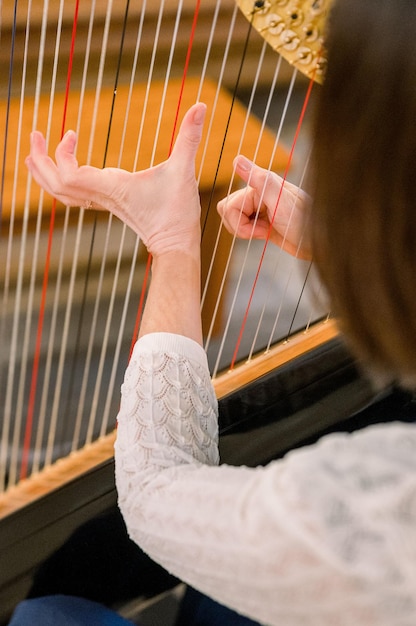 Vertical shot of a woman playing a harp