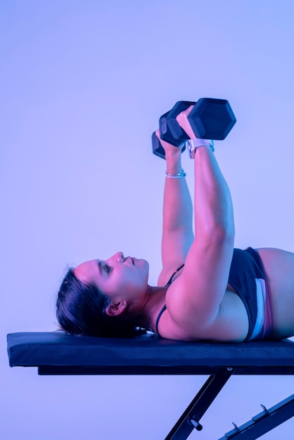 Vertical shot of a woman in sportswear doing bench press close up