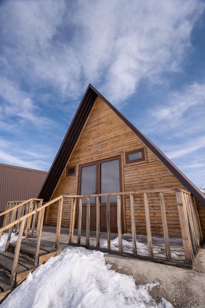 A vertical shot of a wooden cottage surrounded by snow A recreation area in the mountains