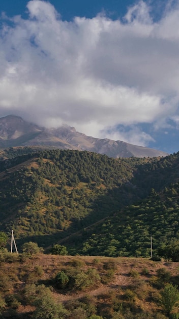 vertical view of mountains under the sky with clouds on a summer day