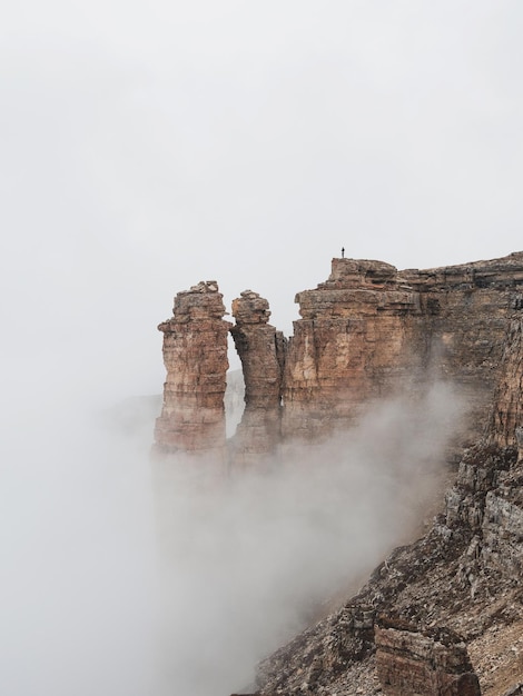 Vertical view of sharp rocks in the fog Mountains in a dense fog Mystical landscape with beautiful sharp rocks in low clouds