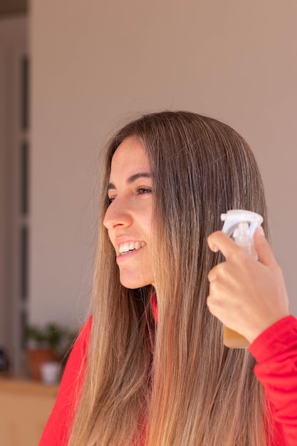 Vertical view side view of young happy smiling woman using hair styling for straight shinny hair