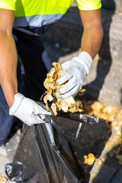 Vertical view of an unrecognizable latin street sweeper picking up leaves and garbage from the street floor