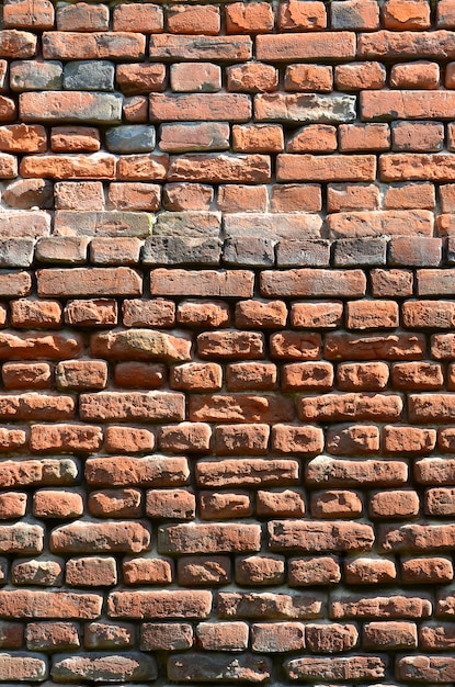 Vertical wall texture of several rows of very old brickwork 