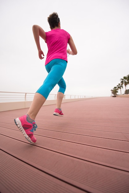 very active young beautiful woman busy running on the promenade along the ocean side to keep up her fitness levels as much as possible