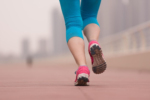 very active young beautiful woman busy running on the promenade along the ocean side with a big modern city in the background to keep up her fitness levels as much as possible