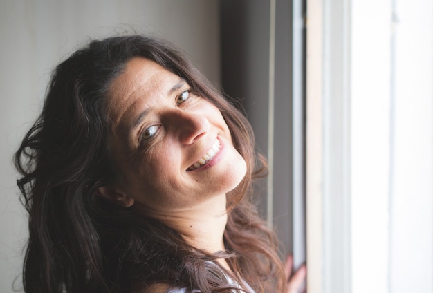 Very attractive Spanish long haired brunette middle aged woman smiling at home