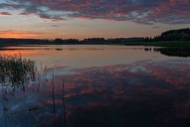 Very beautiful majestic sunset, bright clouds reflection in quiet water