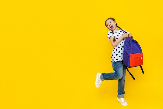 A very cheerful girl with a bag of textbooks lifted her leg up and makes a face the child is very happy with additional classes